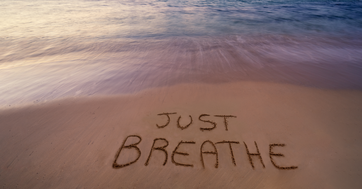 Handwritten Just breathe on sandy beach at sunset
